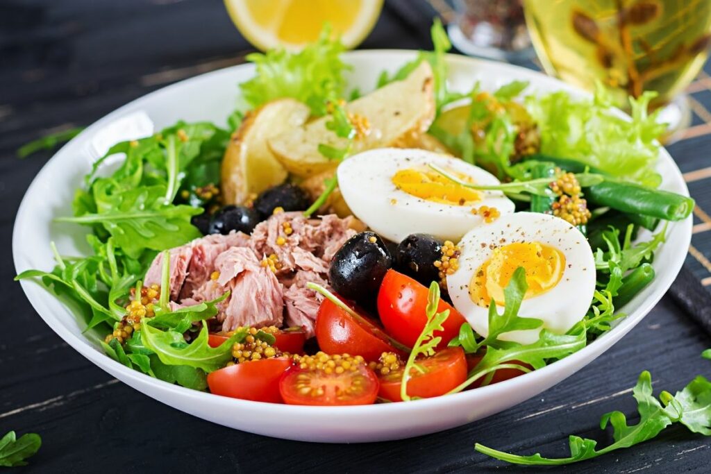 Apprendre le français en cuisinant : La fameuse salade niçoise avec les petites olives de Nice, des œufs, du thon, des tomates, et plein d'autres ingrédients qui changent selon les cuisiniers. A déguster en entrée ou en plat principal...